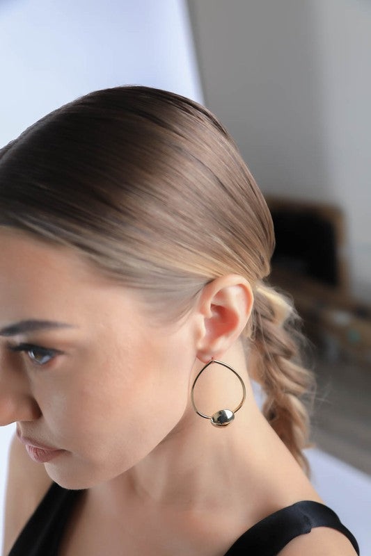 Woman wearing Oval Drop Simple Hoop Earrings in gold, showcasing the irregular oval shape for a modern, minimalist look.