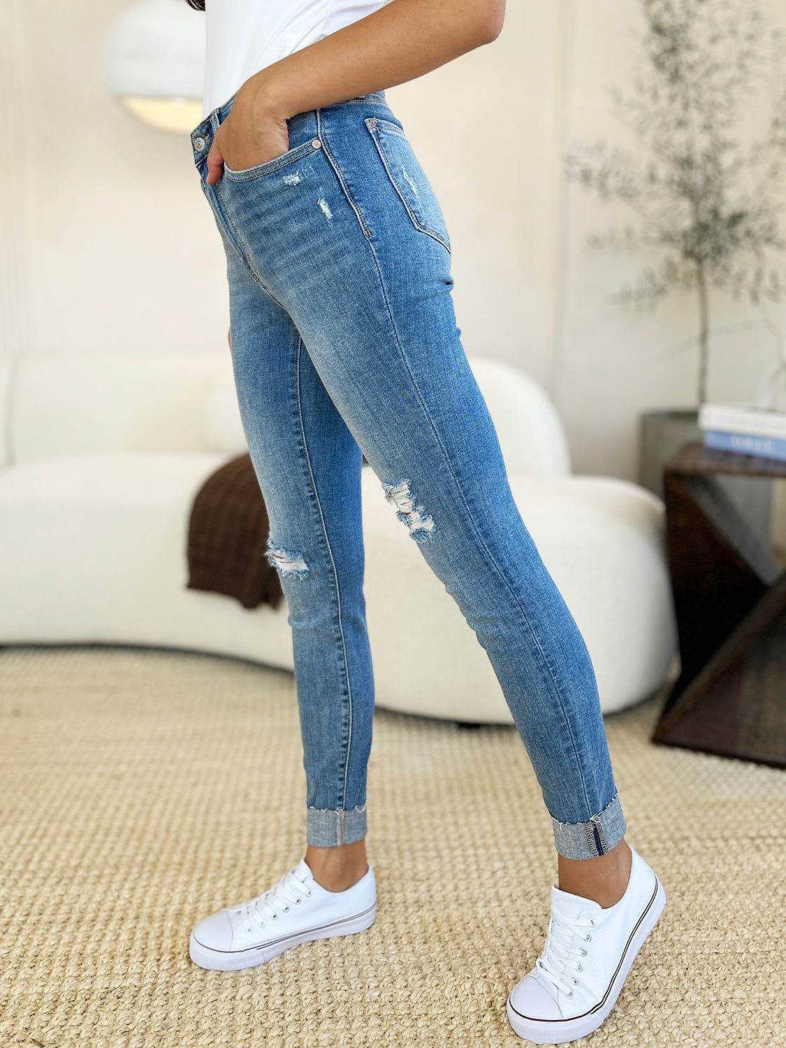 Medium wash Judy Blue Courtney Mid Rise Skinny Jeans shown from the side with distressed details and cuffed skinny hem.