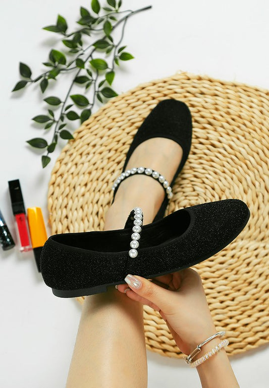 Woman wearing one black Corphee Pearl Strapped Glitter Ballerina while holding the other shoe in her hand.