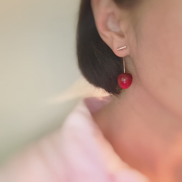 Woman wearing Sweet Cherry Drop Earrings with bold red cherry charms dangling playfully