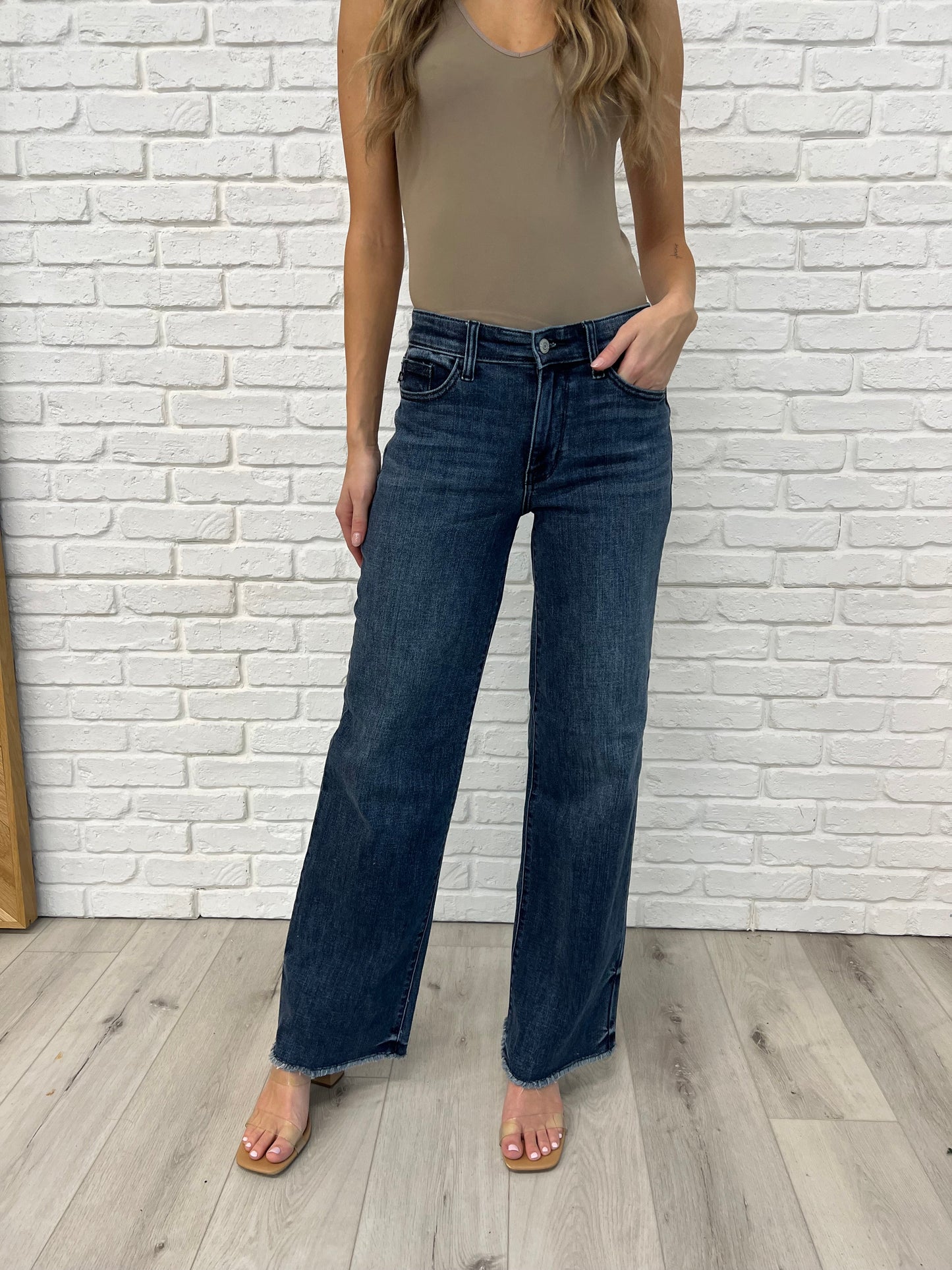 Addie Mid Rise Jeans by Judy Blue in a dark vintage wash featuring a wide leg silhouette, raw cut off hem, release hem dye detail, and zip fly closure.