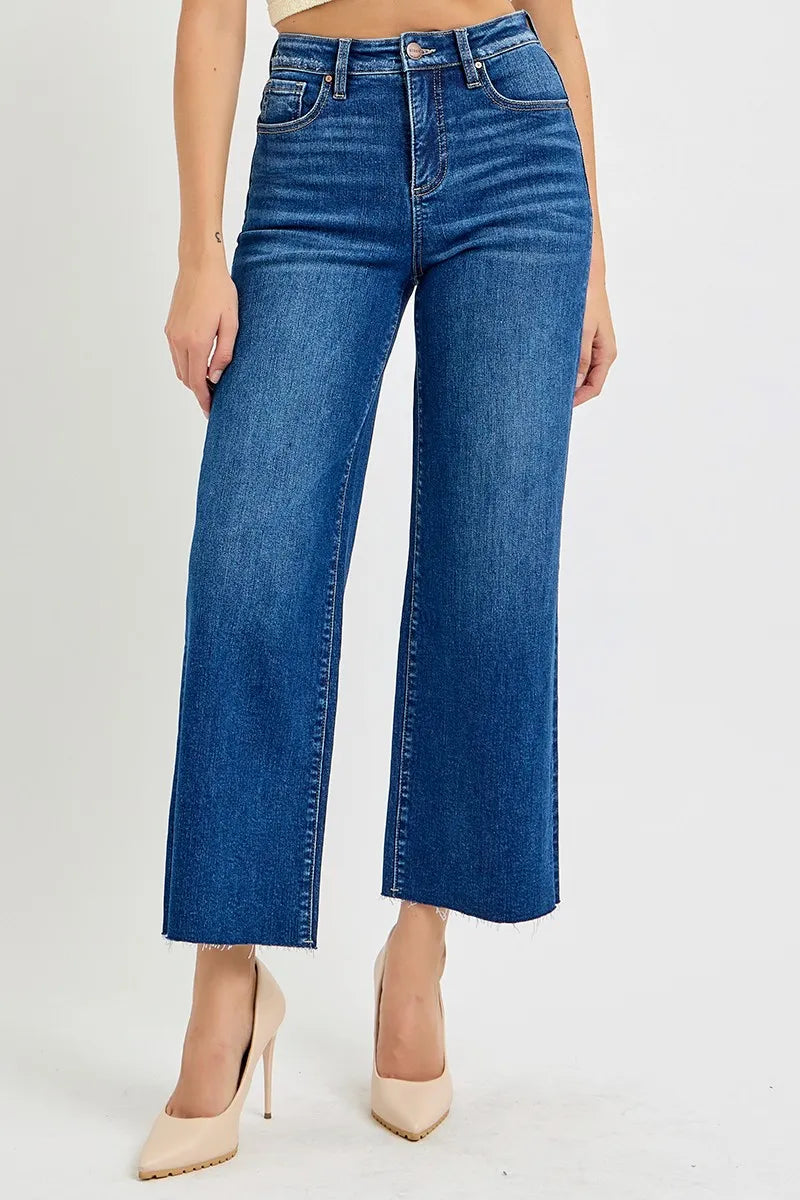Woman wearing Adrina tummy control high rise wide crop jeans in dark wash, front view with raw hem detail.