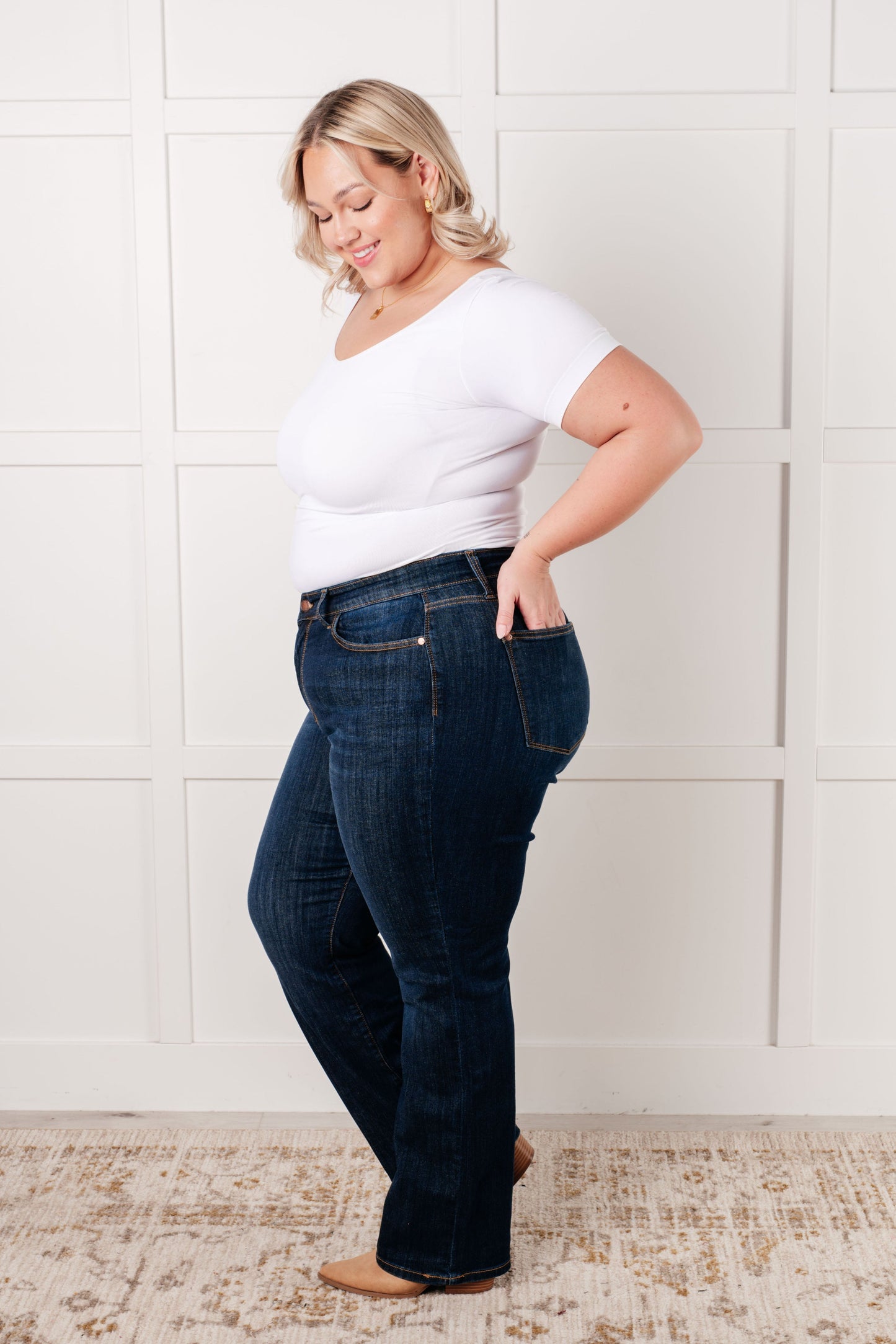 Side view of plus size model wearing the Judy Blue dark wash high-rise straight-leg jeans with a zip fly, 4-way stretch, and a non-distressed design.