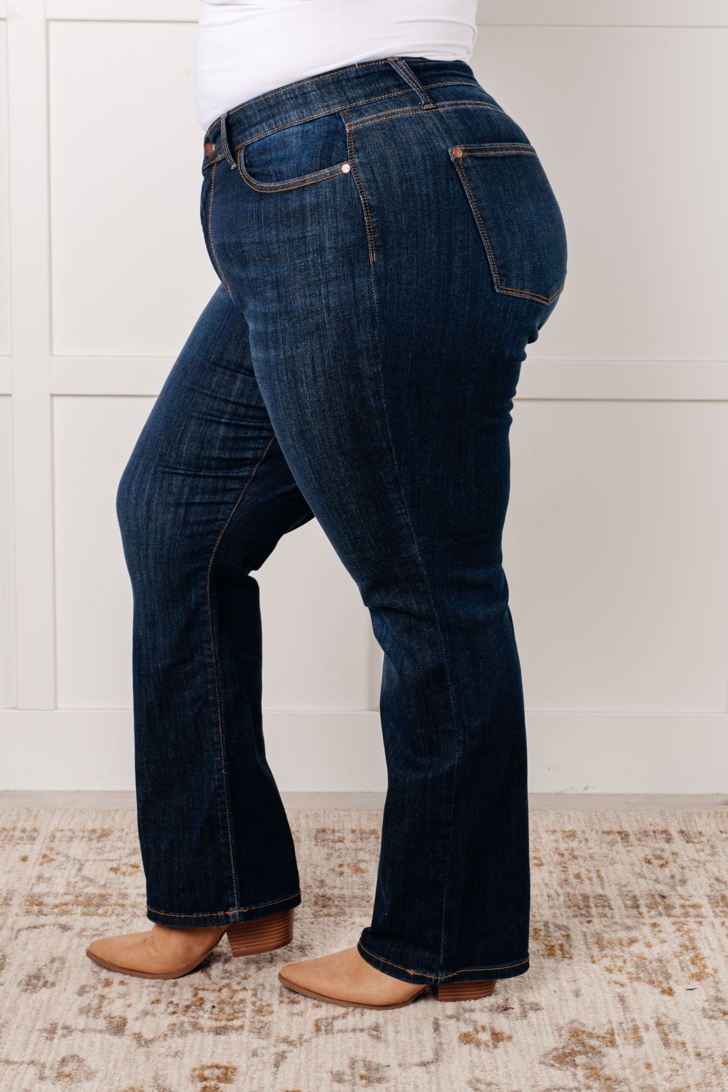 Close up side view of plus size model wearing the Judy Blue dark wash high-rise straight-leg jeans with a zip fly, 4-way stretch, and a non-distressed design.