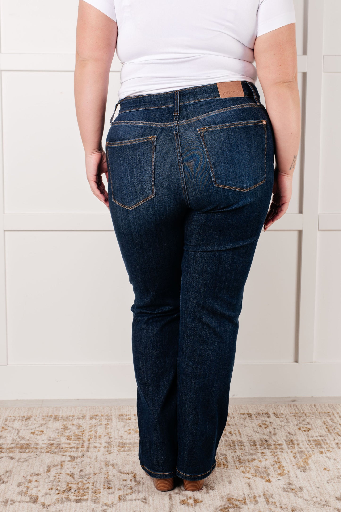 Back view of plus size model wearing the Judy Blue dark wash high-rise straight-leg jeans with a zip fly, 4-way stretch, and a non-distressed design.