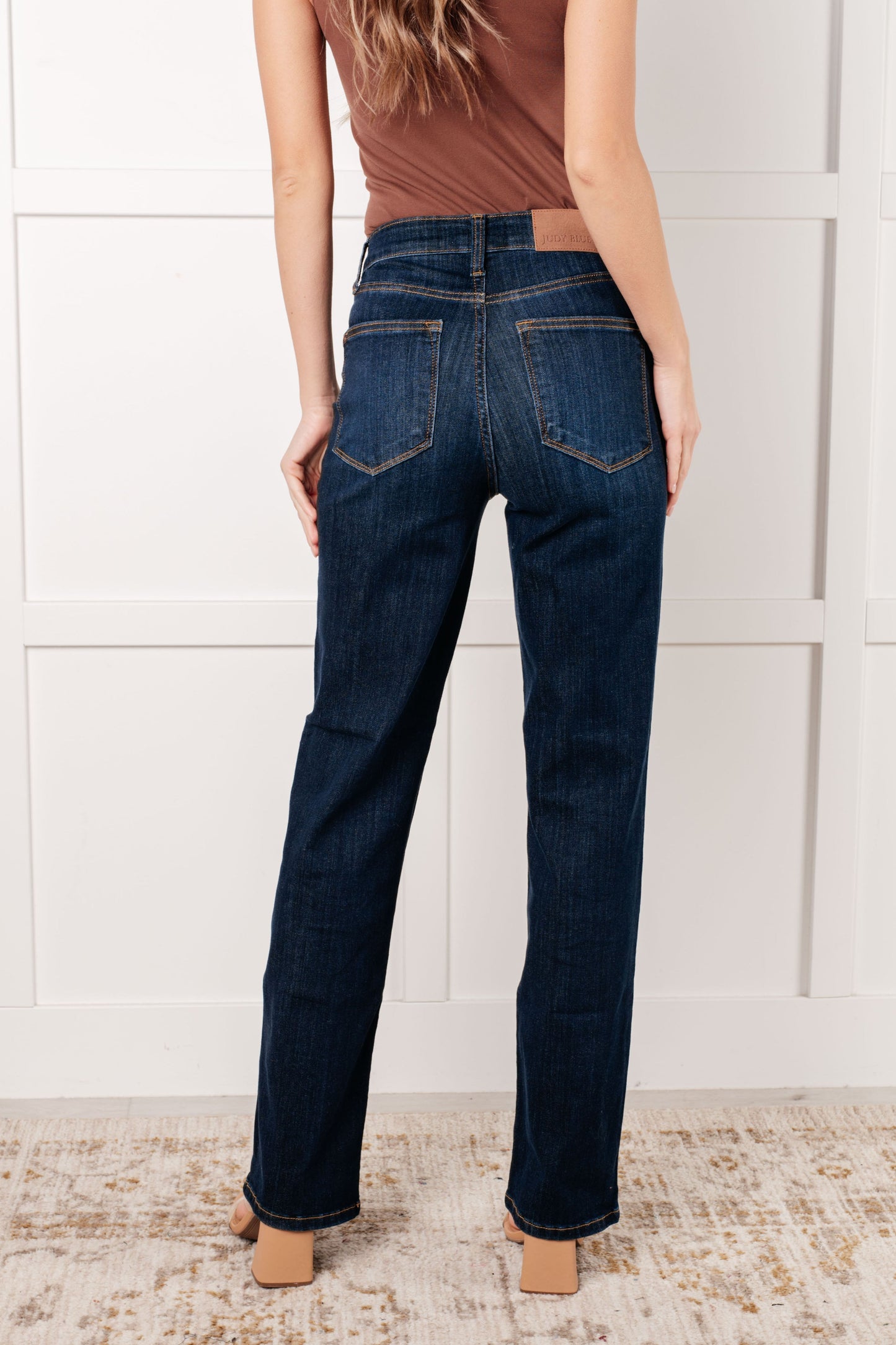 Back view of model wearing the Judy Blue dark wash high-rise straight-leg jeans with a zip fly, 4-way stretch, and a non-distressed design.