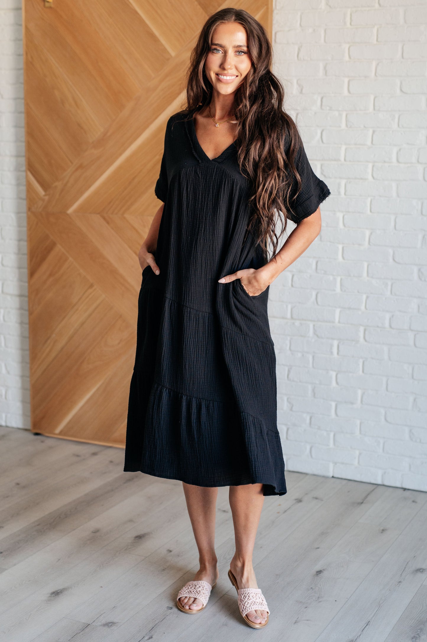 Woman wearing black Dani Dolman Sleeve Dress with tiered midi design, V-neckline, and breezy dolman sleeves, front view.