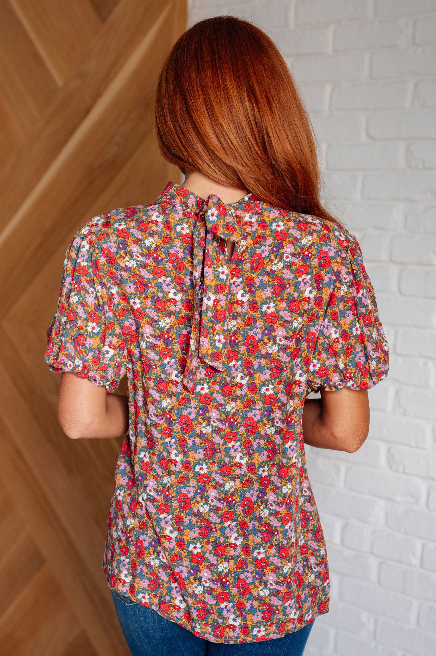 Back view of Leigh floral boho blouse with mock neck, floral print, and breezy balloon sleeves in lightweight poplin fabric.