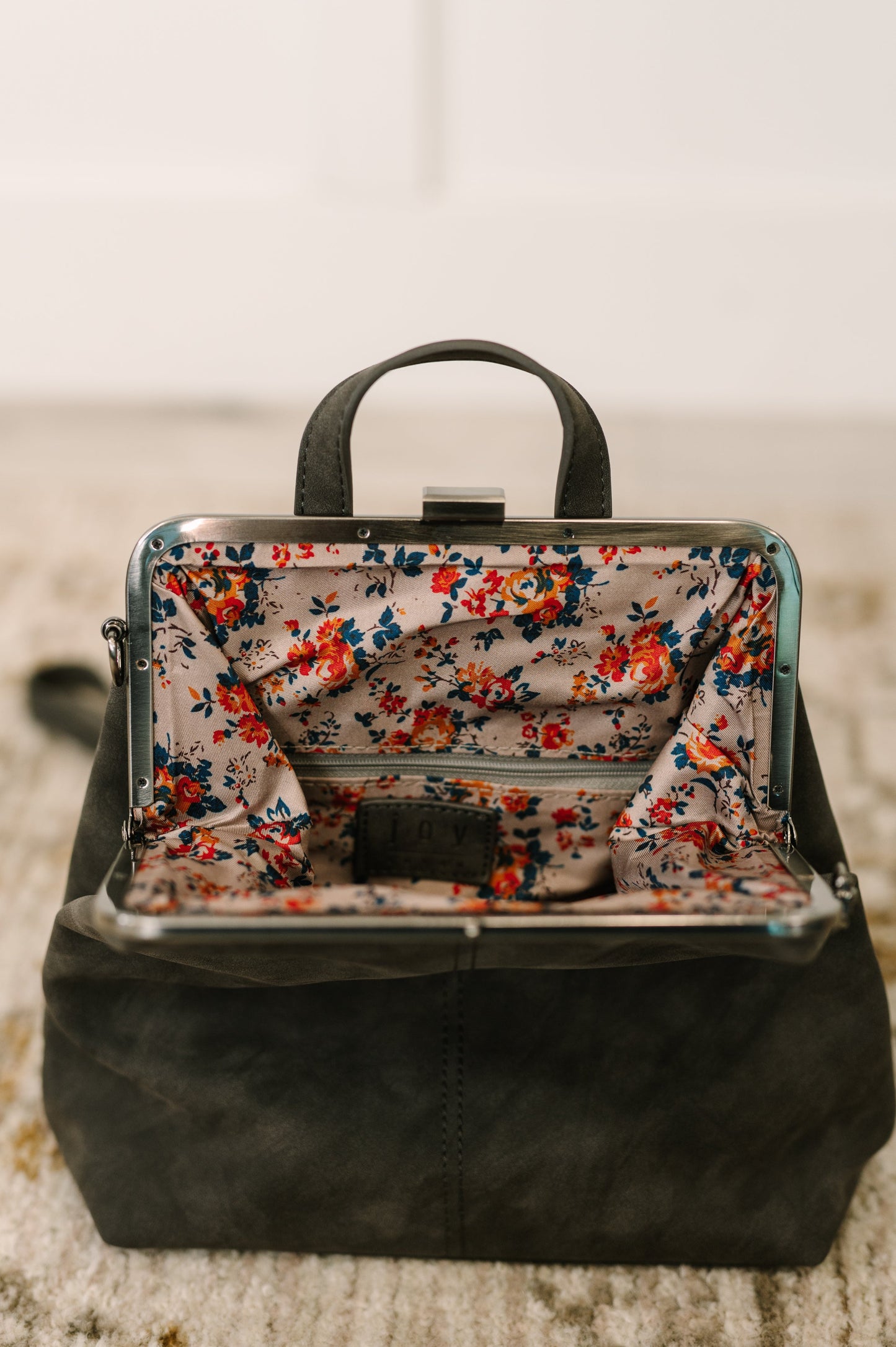 Interior view of the Bridget Mini Charcoal Backpack featuring a zippered pocket and stylish floral print lining.