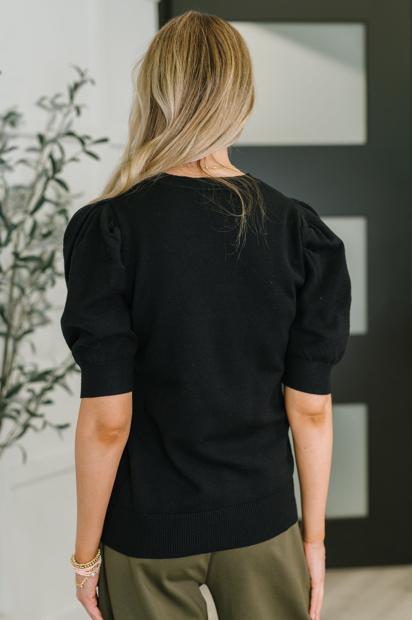Giselle Puff Sleeve Blouse in Black, back view showing ribbed knit and banded hemline.