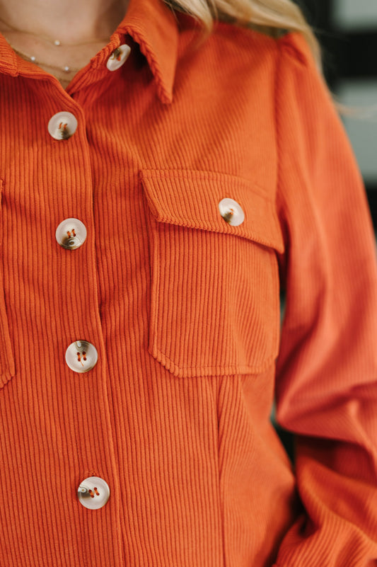 Close-up of Clea Corduroy Shirt Dress orange corduroy fabric and pocket detail.
