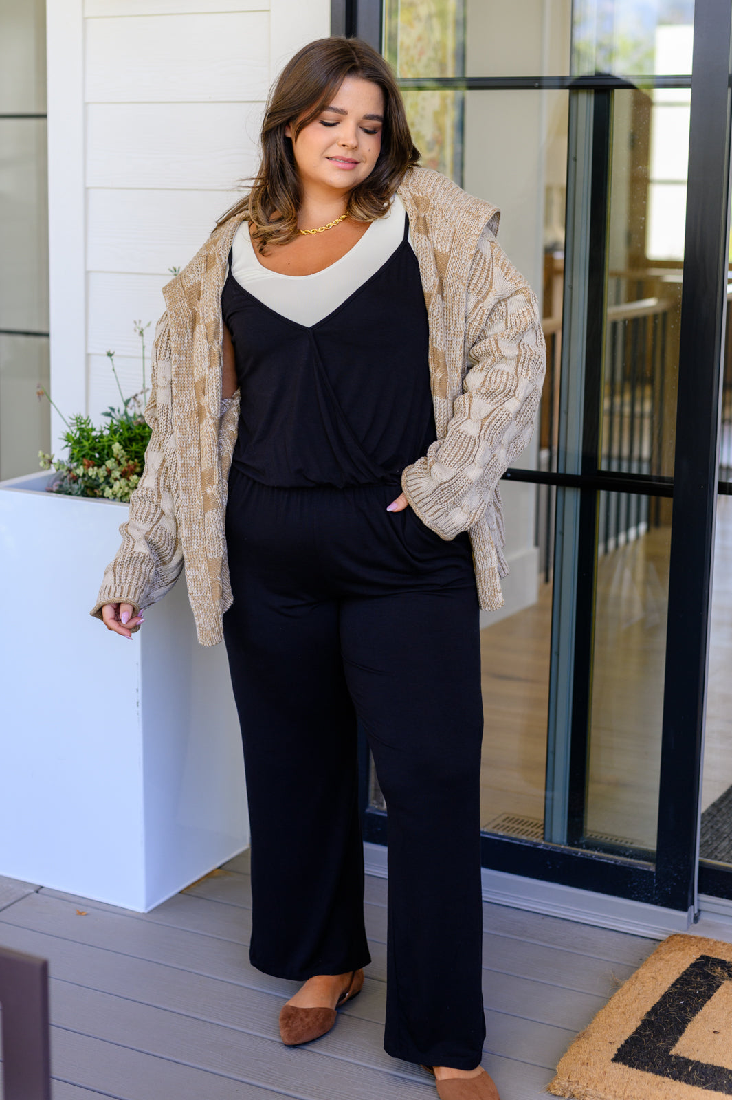 Plus size full body view of Viola Jumpsuit in Black with gold chain necklace and cardigan