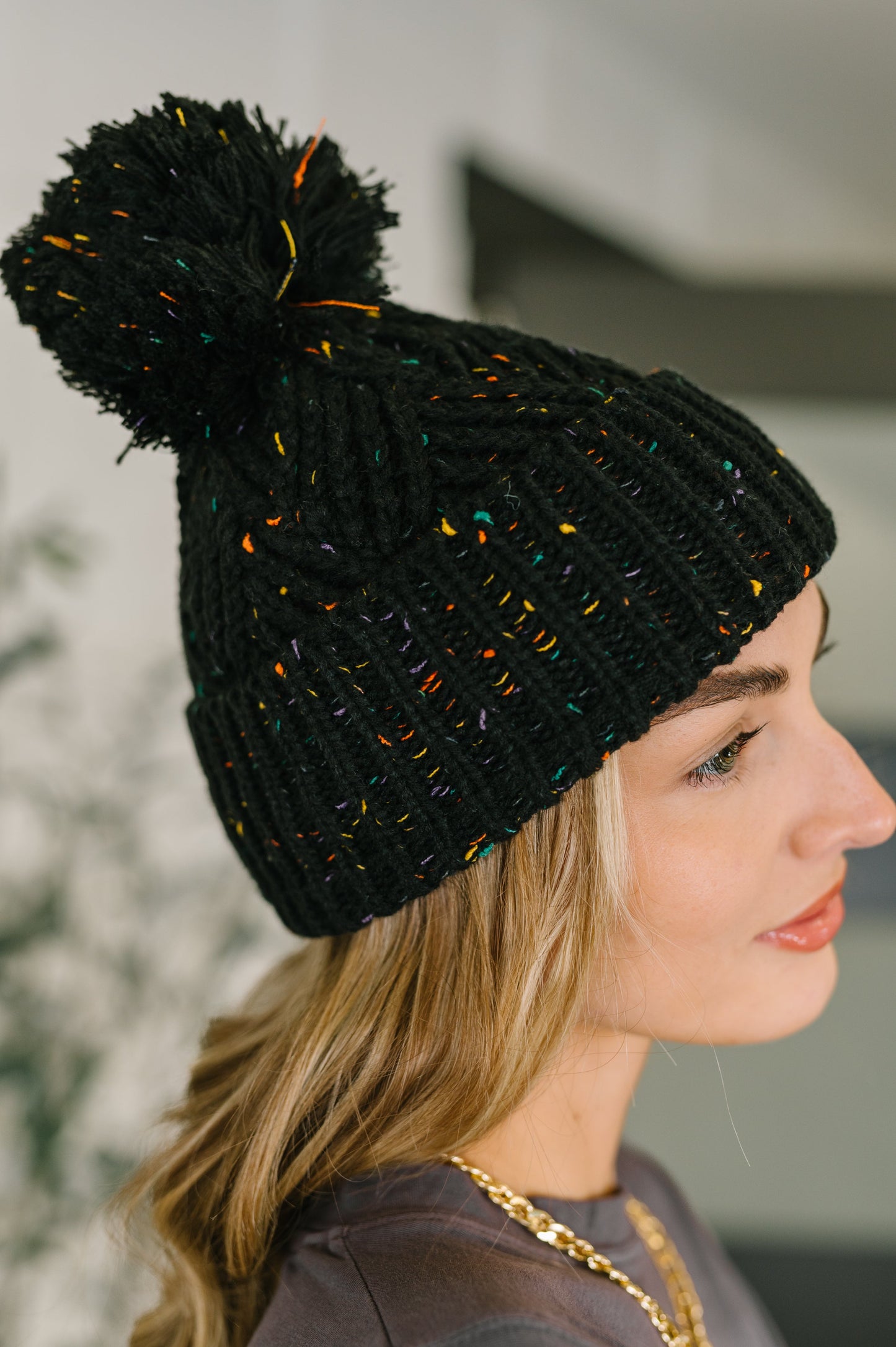 Side angle of Cover Your Ears Pom Pom Beanie highlighting speckled knit pattern.
