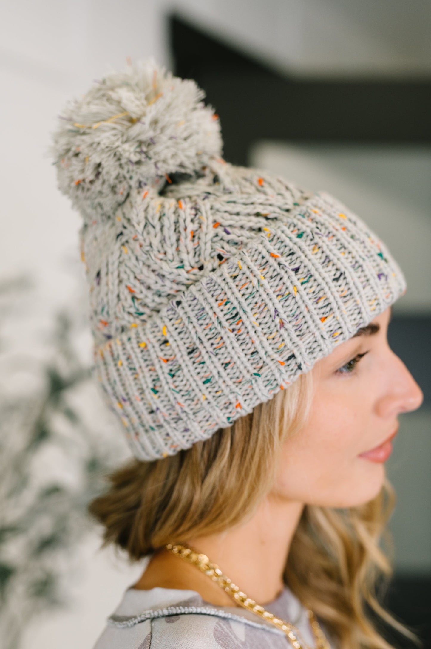Side angle of Cover Your Ears Pom Pom Beanie highlighting soft knit and pom detail.