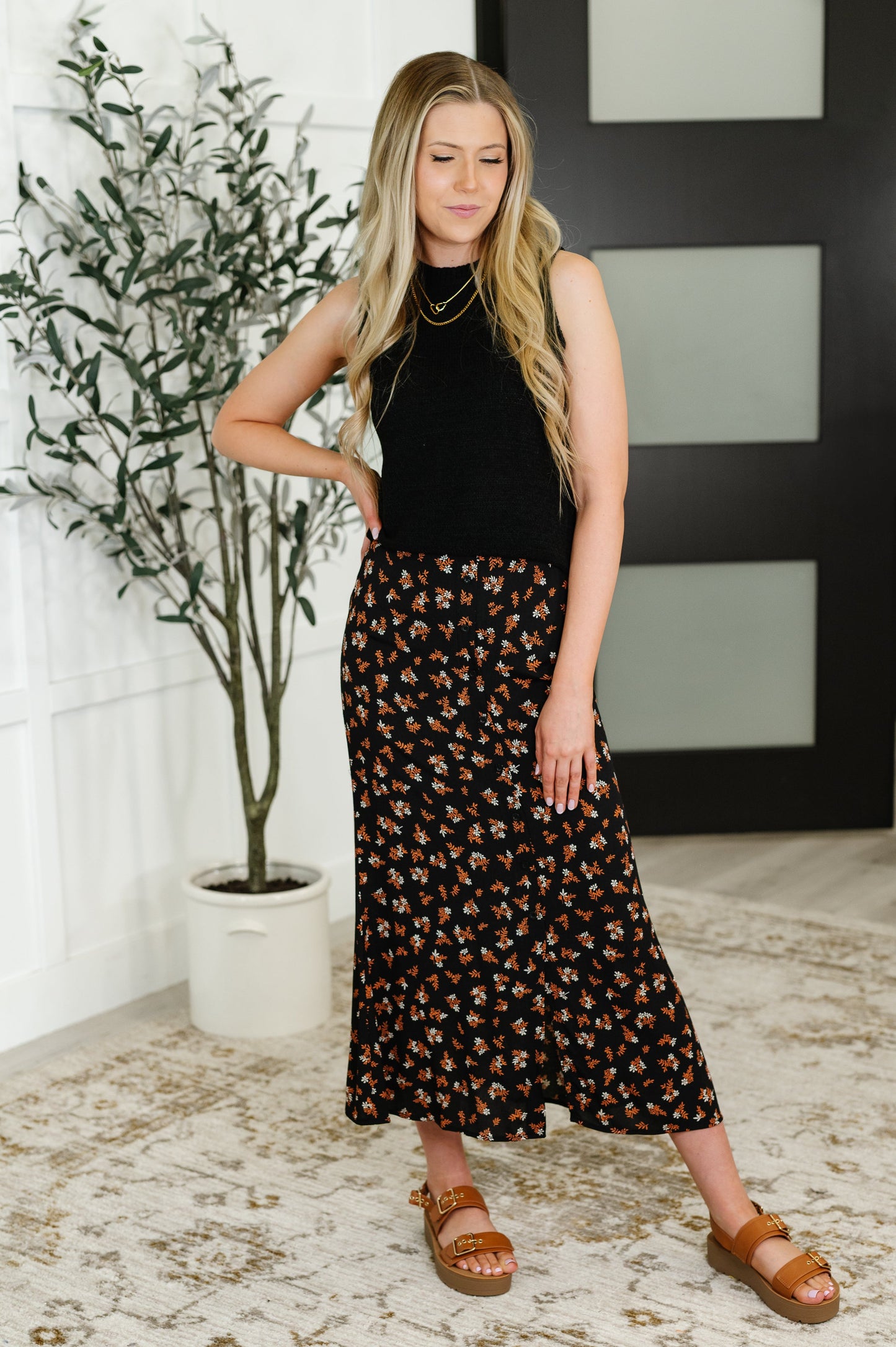 Full body front view of model wearing the Luisa Midi Skirt in black with rust and white floral print, highlighting the high waist and flowy silhouette.