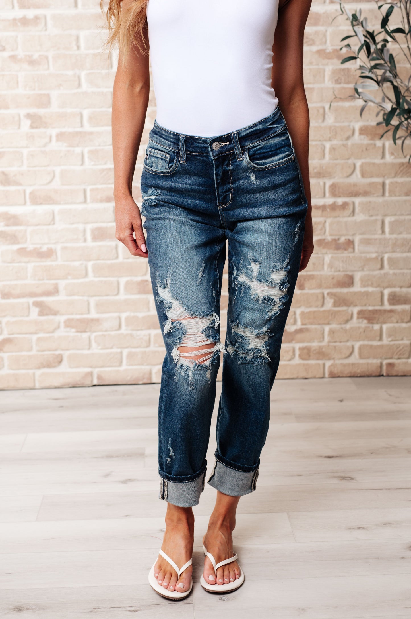 Front view of Danny mid rise boyfriend jeans in dark wash with heavy distressing, cuffed hem, and relaxed fit.