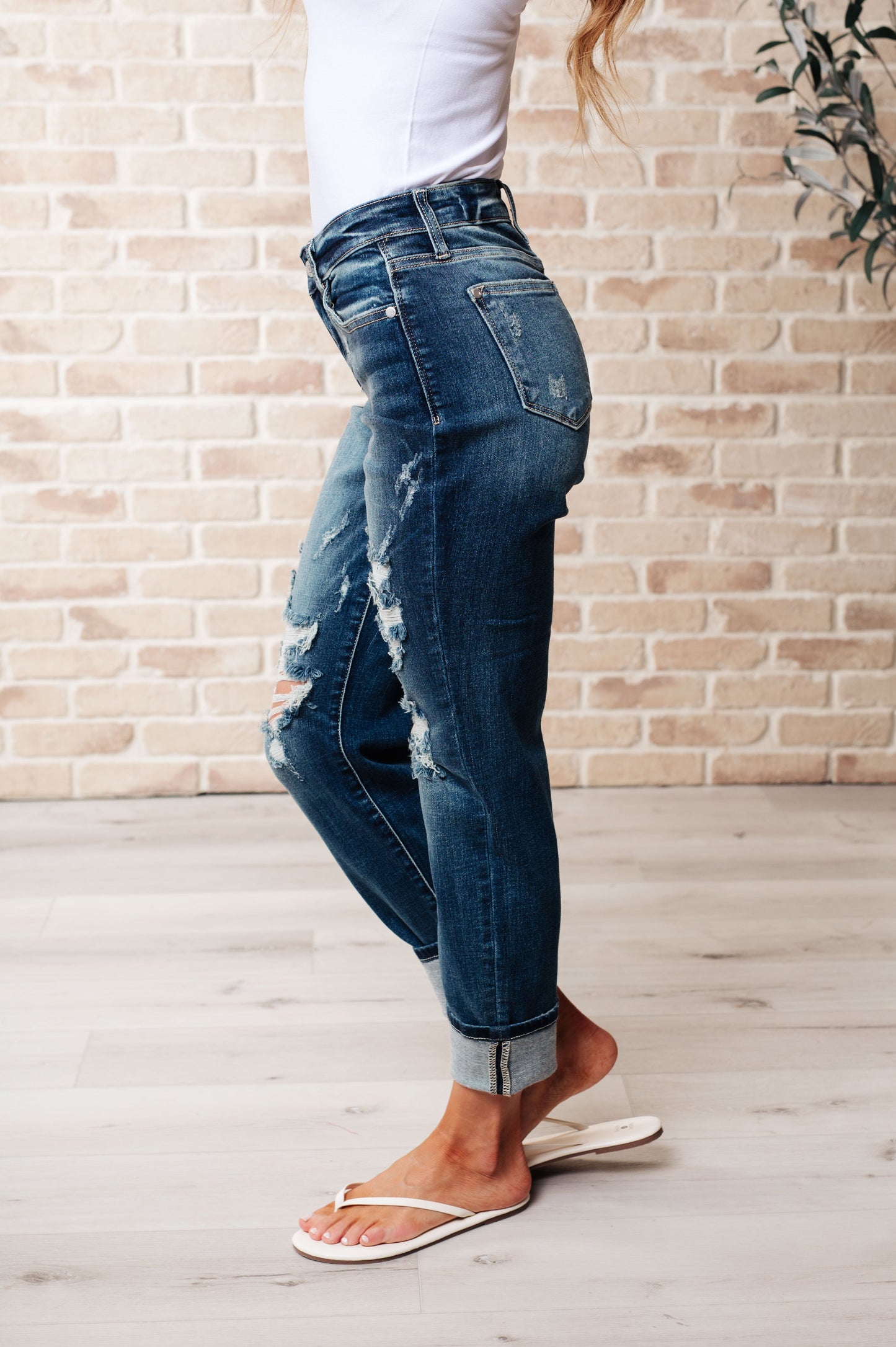 Side view of Danny boyfriend jeans featuring mid rise fit, dark wash denim, heavy distressing, and cuffed hem.