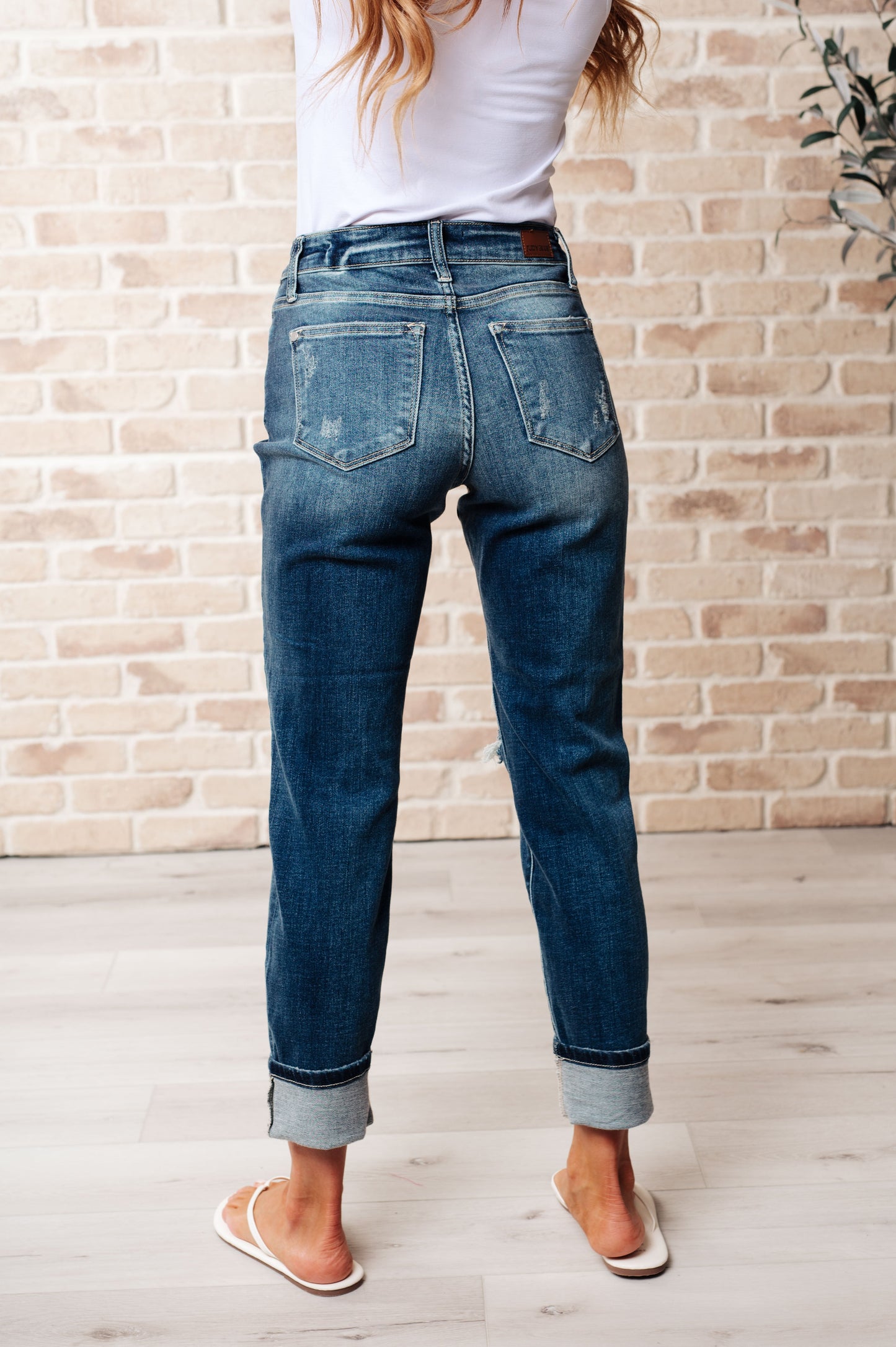 Back view of Danny mid rise boyfriend jeans in dark wash showing relaxed fit, classic back pockets, and optional cuffed hem.