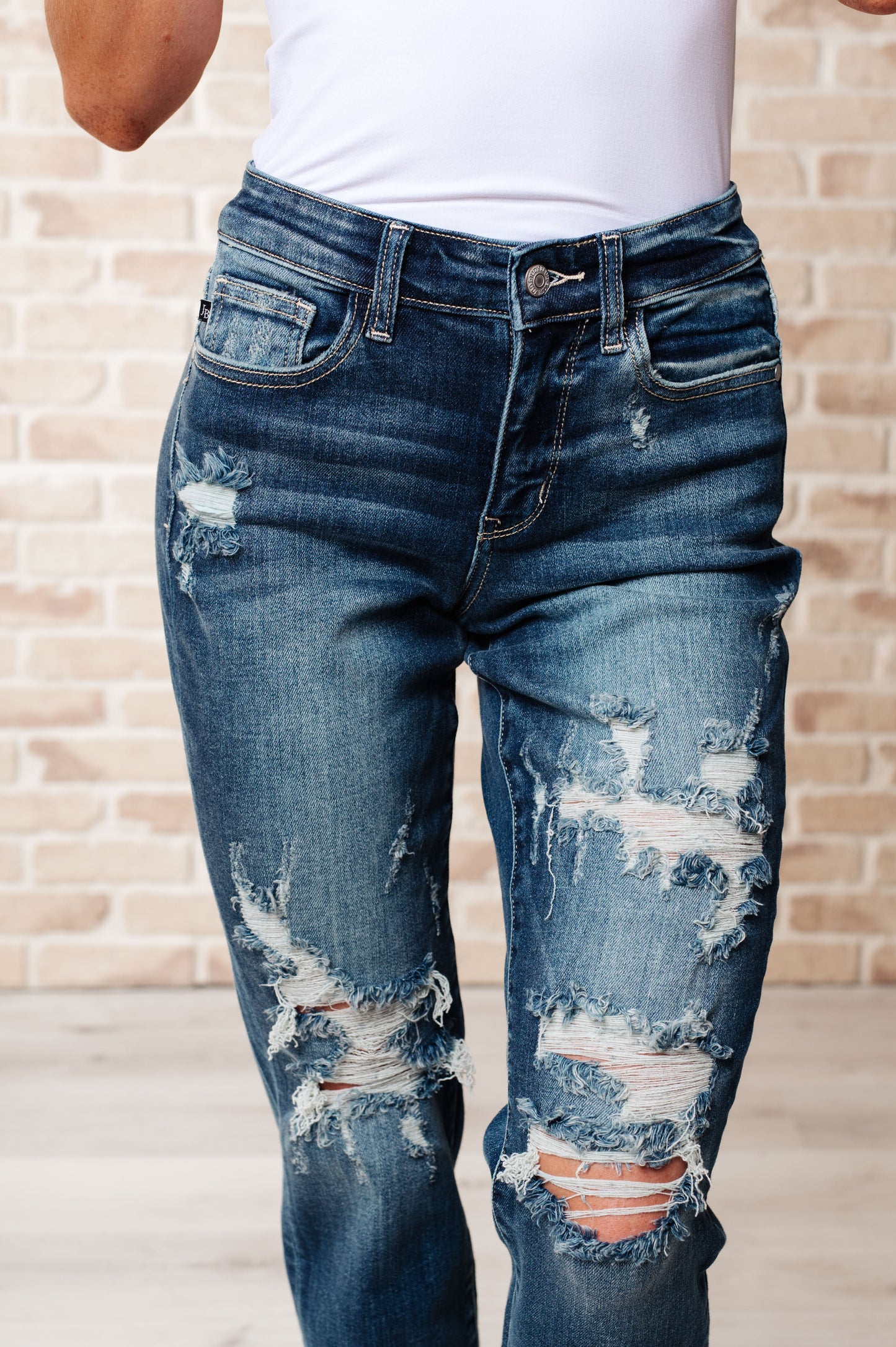 Close-up front view of Danny boyfriend jeans showing mid rise fit, heavy distressing, and dark wash denim with cuffed hem.