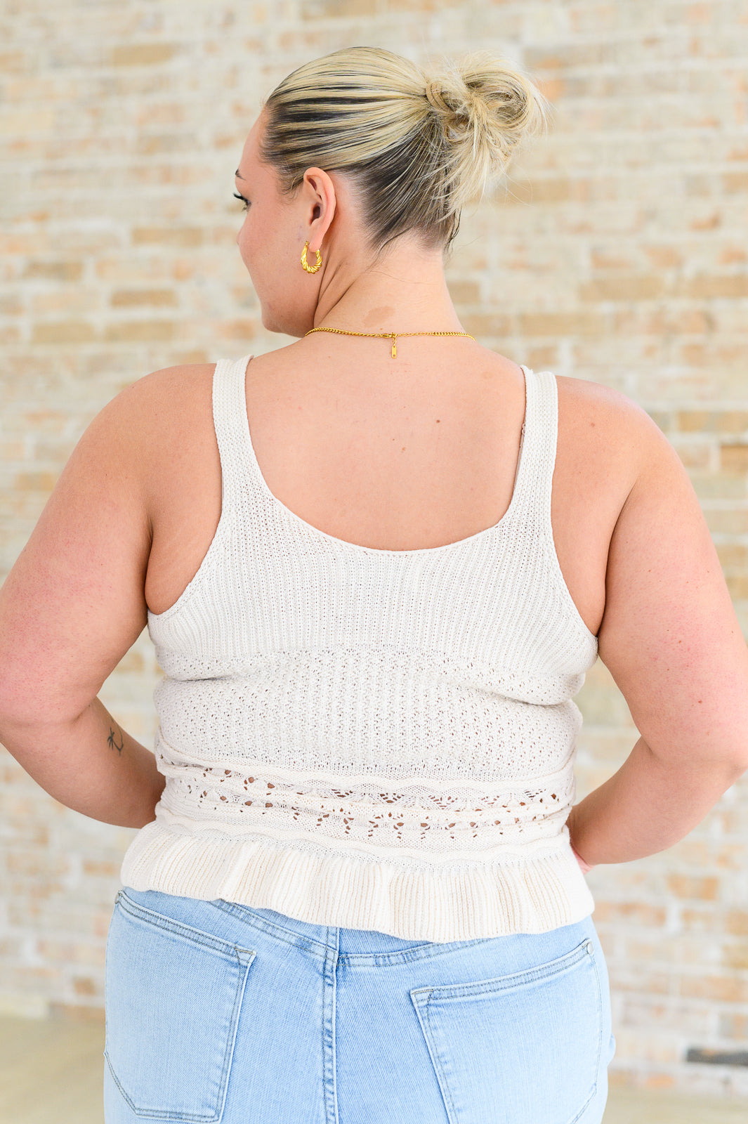 Back view of plus size woman wearing the Amie Ruffle Knit Tank Top in ivory, highlighting the ruffle trim hem and textured knit design.