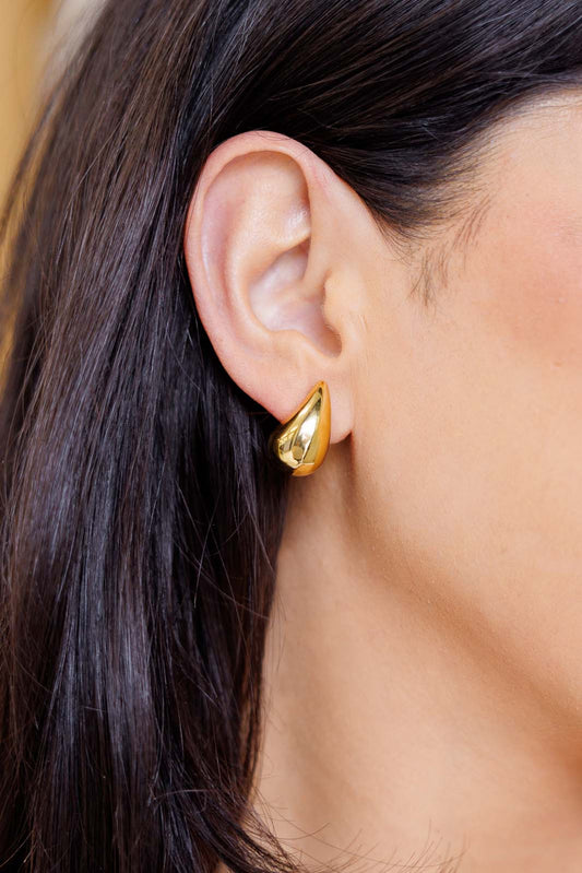 Woman wearing gold teardrop earrings, highlighting sleek, classic style.