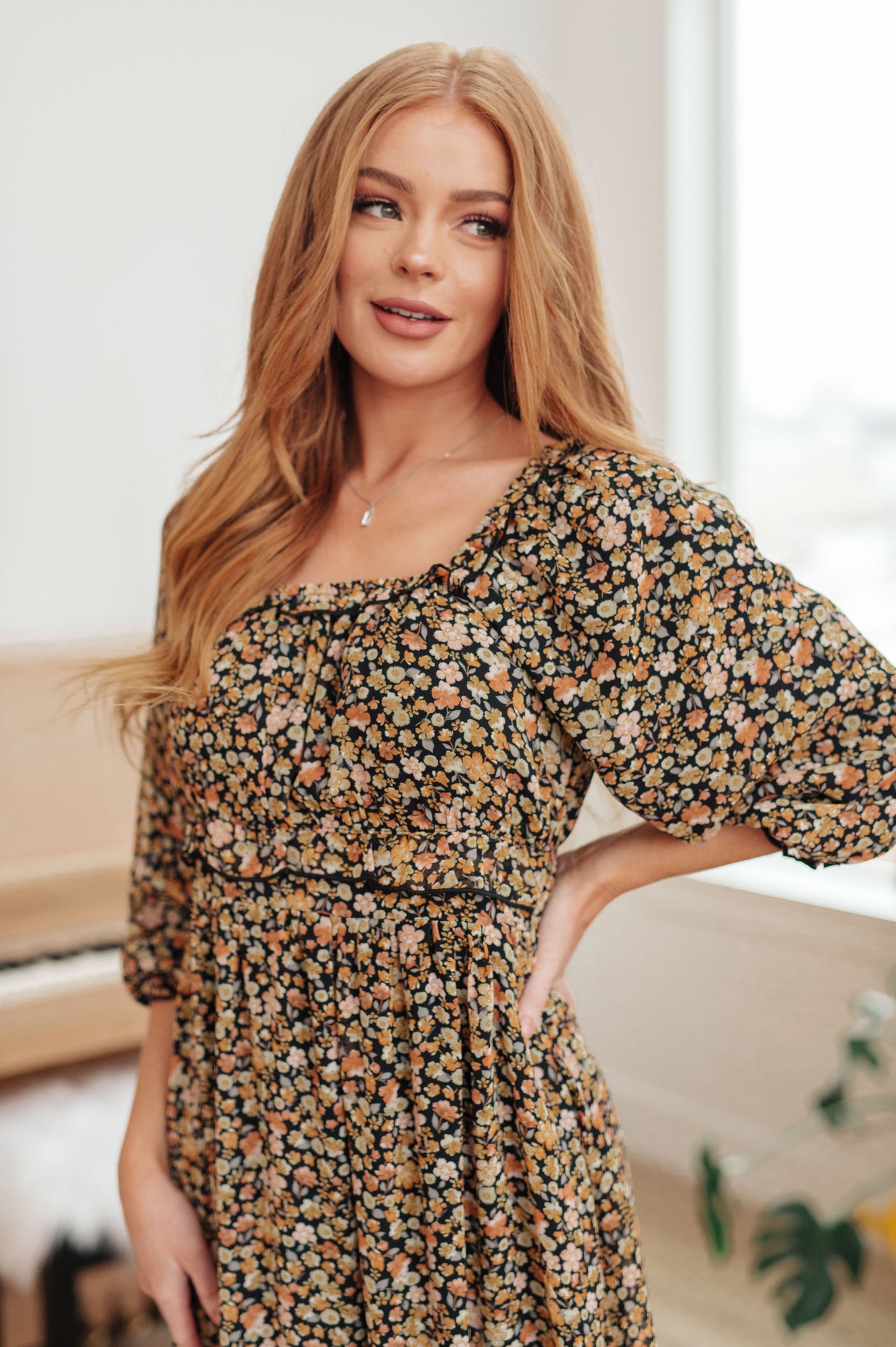 Black/orange floral maxi dress with 3/4 sheer sleeves and ruffle accents, close up.