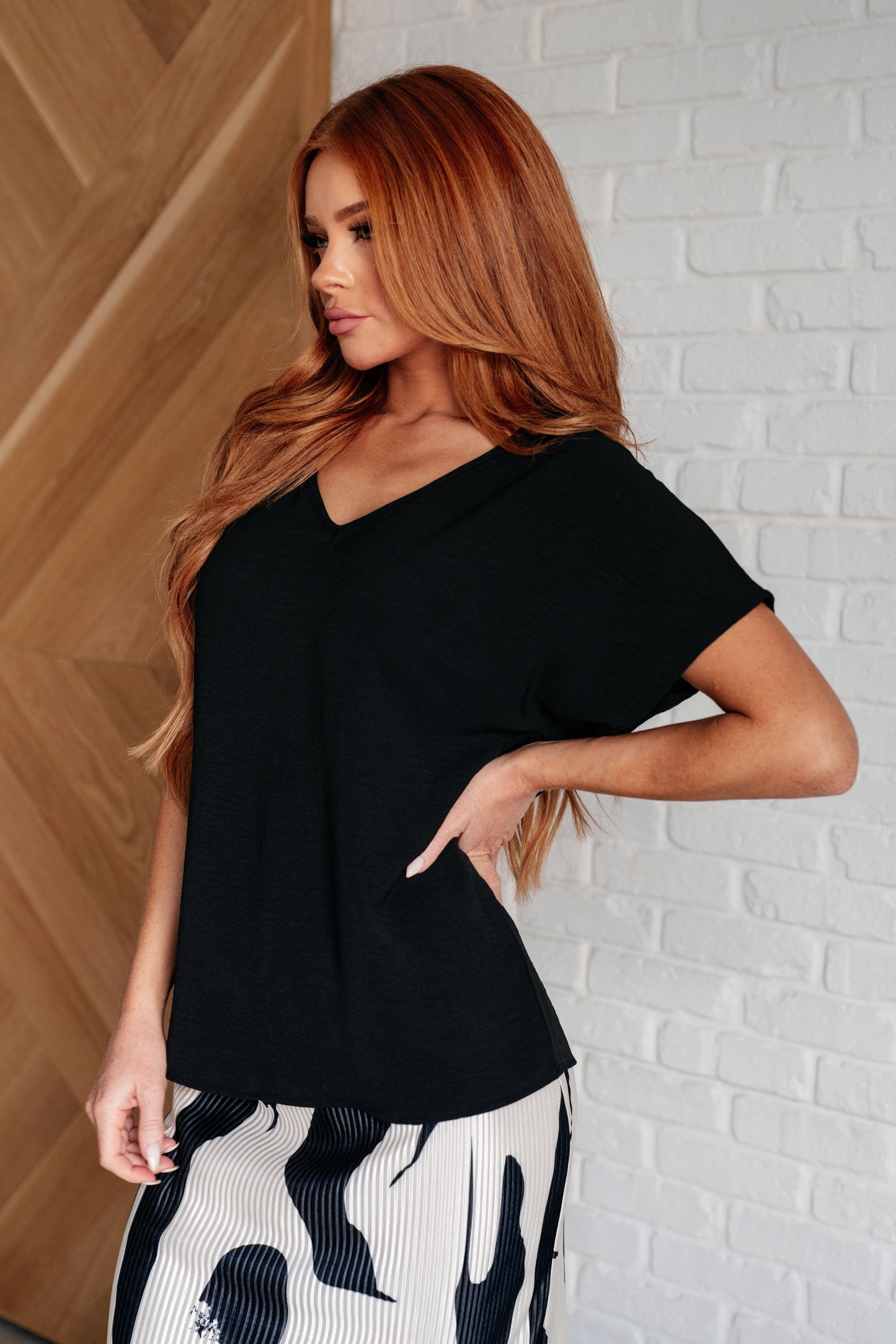 Side angle of Freya black V-neck top showing relaxed fit and soft woven fabric.