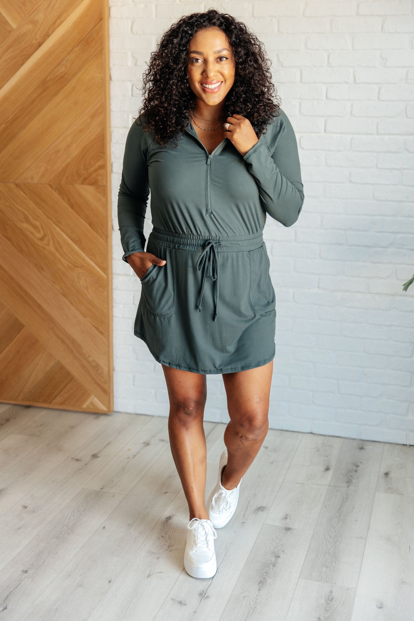 Women's Rowan Long Sleeve Hoodie Romper in Smoked Spruce by Rae Mode, featuring brushed microfiber fabric, V-neck with half zip, hood, patch pockets, long raglan sleeves, cased elastic drawstring waist, and lined shorts.