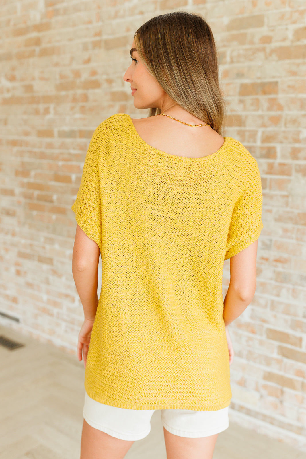Back view of saffron Eliora Knit Top showing ribbed hemline and short dolman sleeves.