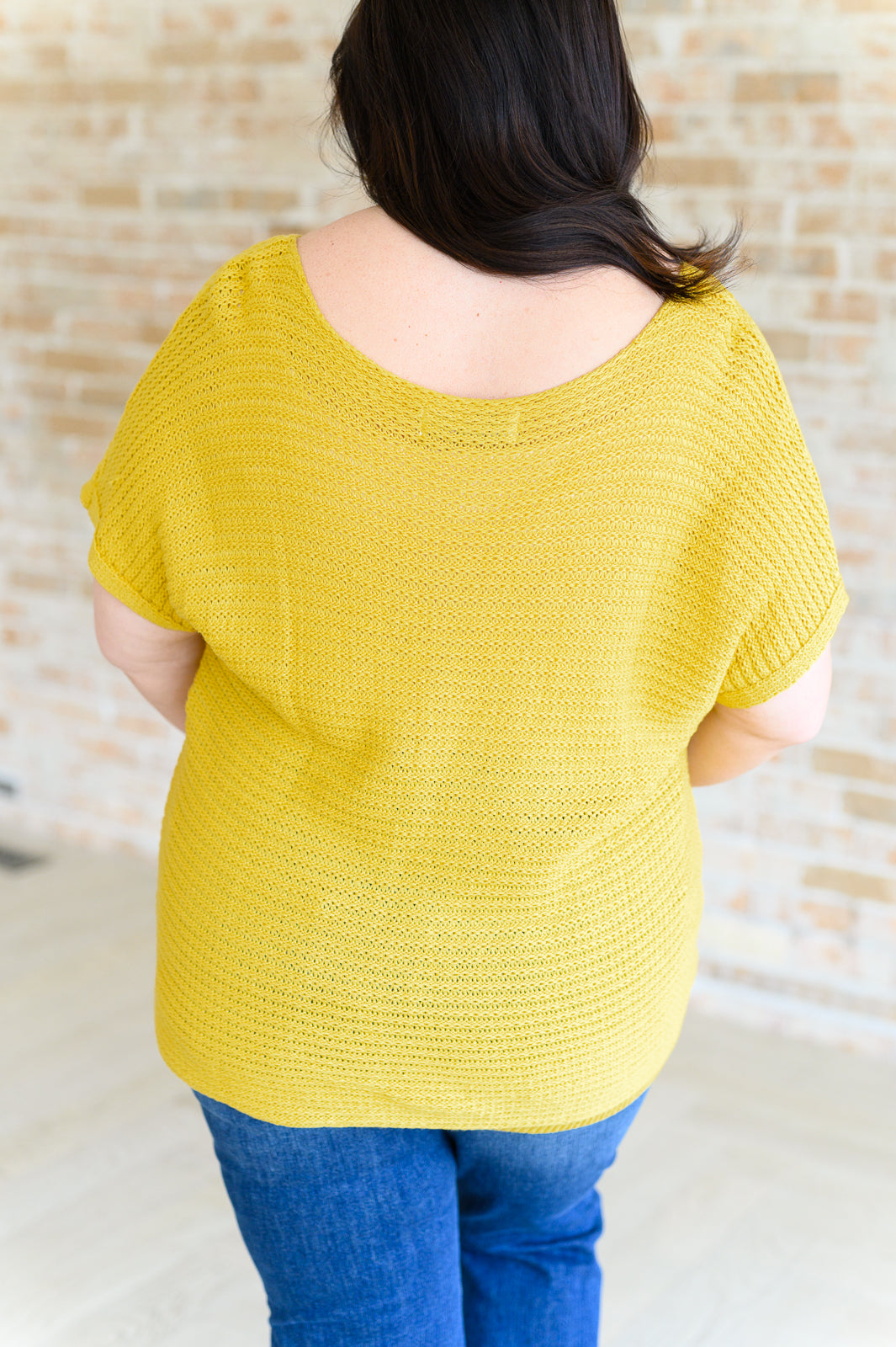 Plus size back view of Eliora Knit Top in saffron with dolman sleeves and ribbed hemline detail.