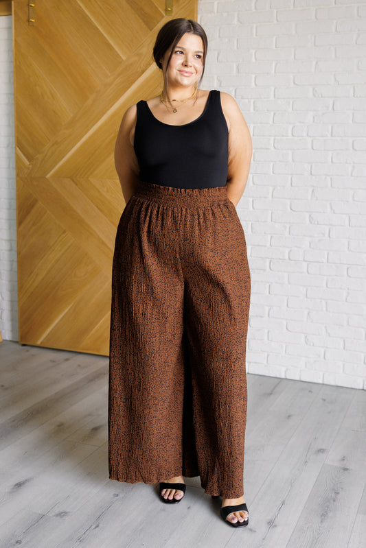 Plus size model wearing Harmony High Rise Wide Leg Pants in brown with smocked waist and dots.