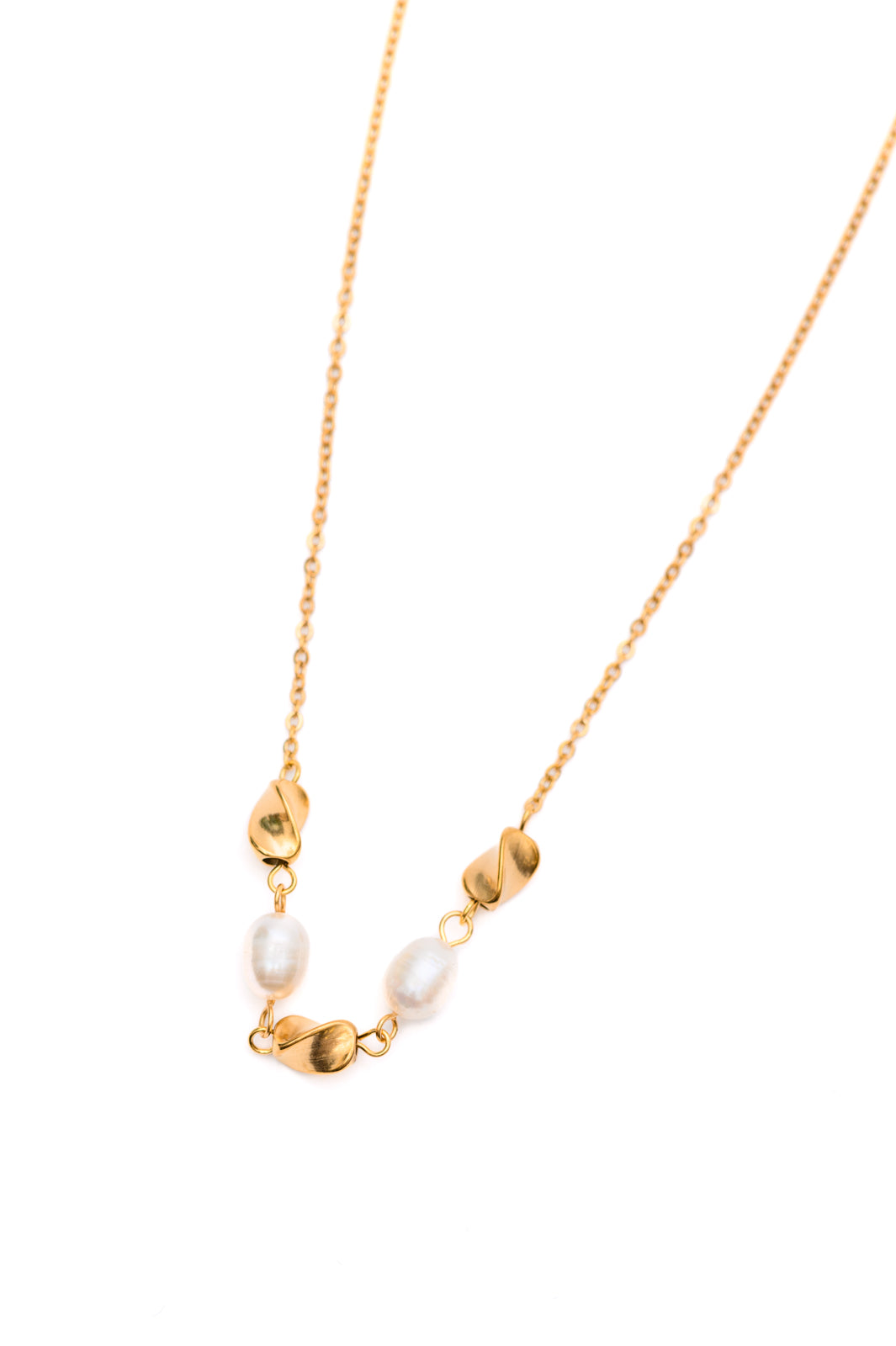 Flat lay of pearl necklace with gold charms on white background