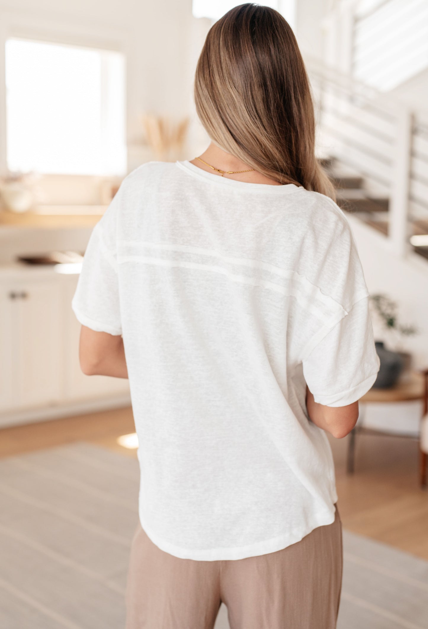 Back view of Khloe Henley Top in ivory, highlighting the high-low hemline and lightweight woven fabric.