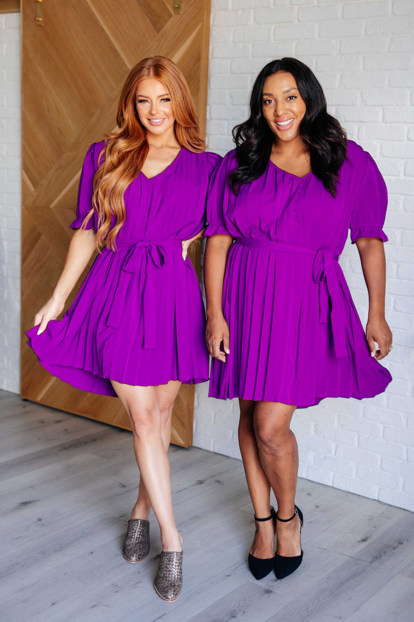 Two women in Hoda Pleated Chiffon Dress, front view with button-up V-neck, puff sleeves, and pleated skirt.