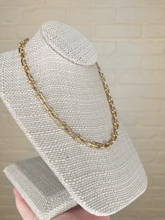 Angled view of the Abigail Link Necklace on a display, highlighting the bold gold links and luxurious shine.