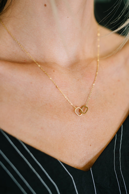 Model styling In This Together Necklace featuring dainty interlocking gold-plated rings with sparkling zirconia diamonds.