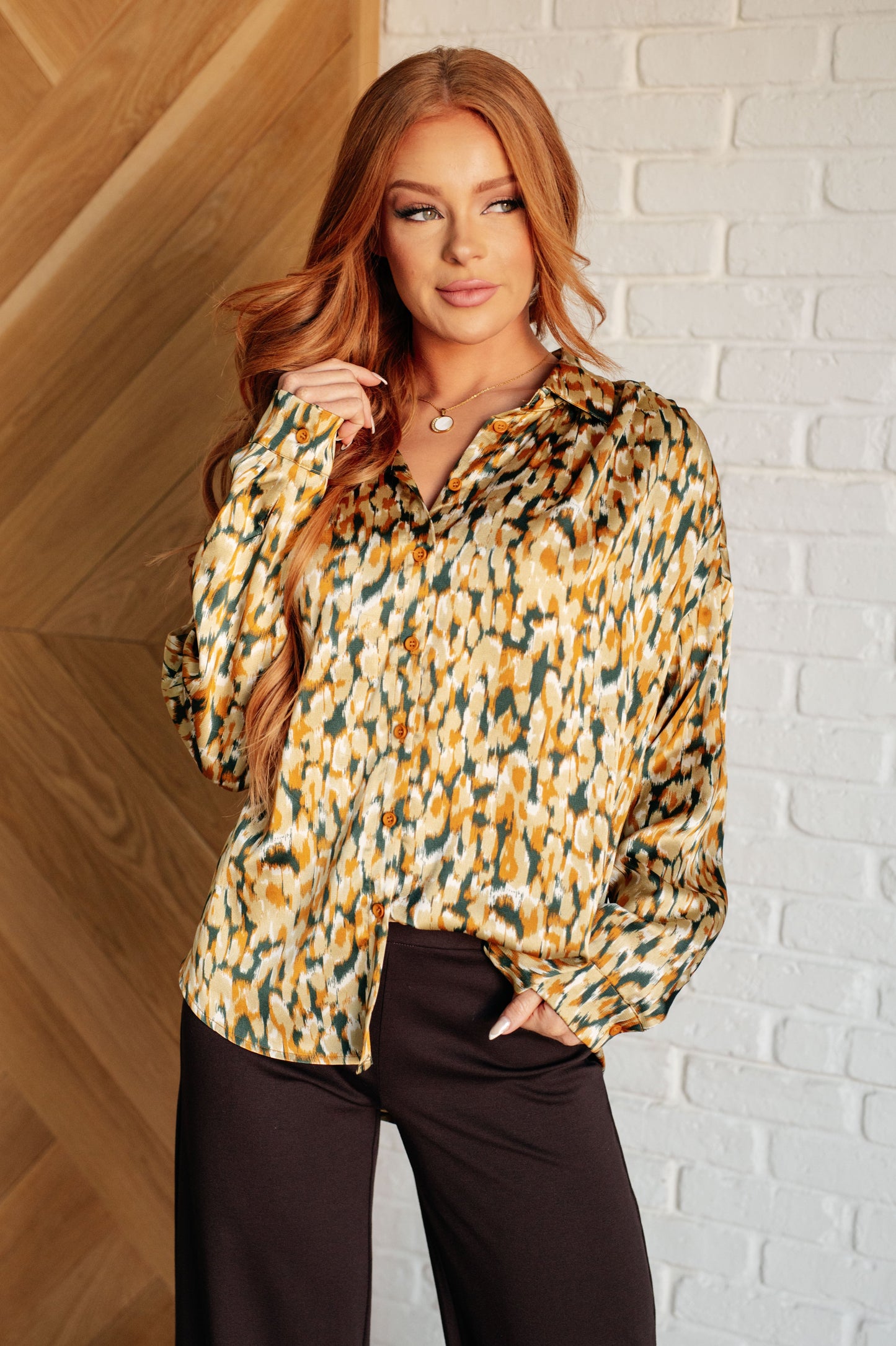 Model wearing Kathryn Satin Button Up Blouse in autumn gold with collared neckline and abstract print