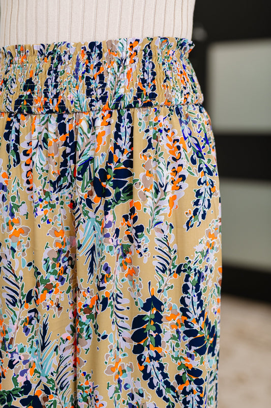 Close up of beige floral pants showing smocked waistband and ruffle trim.