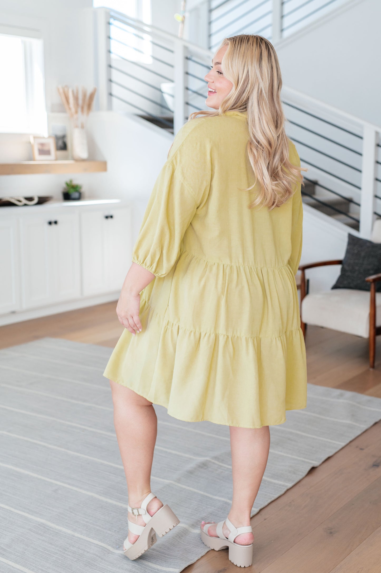Back view of plus size model in Jessie Tiered Mini Dress pear green showing tiered skirt and relaxed silhouette.