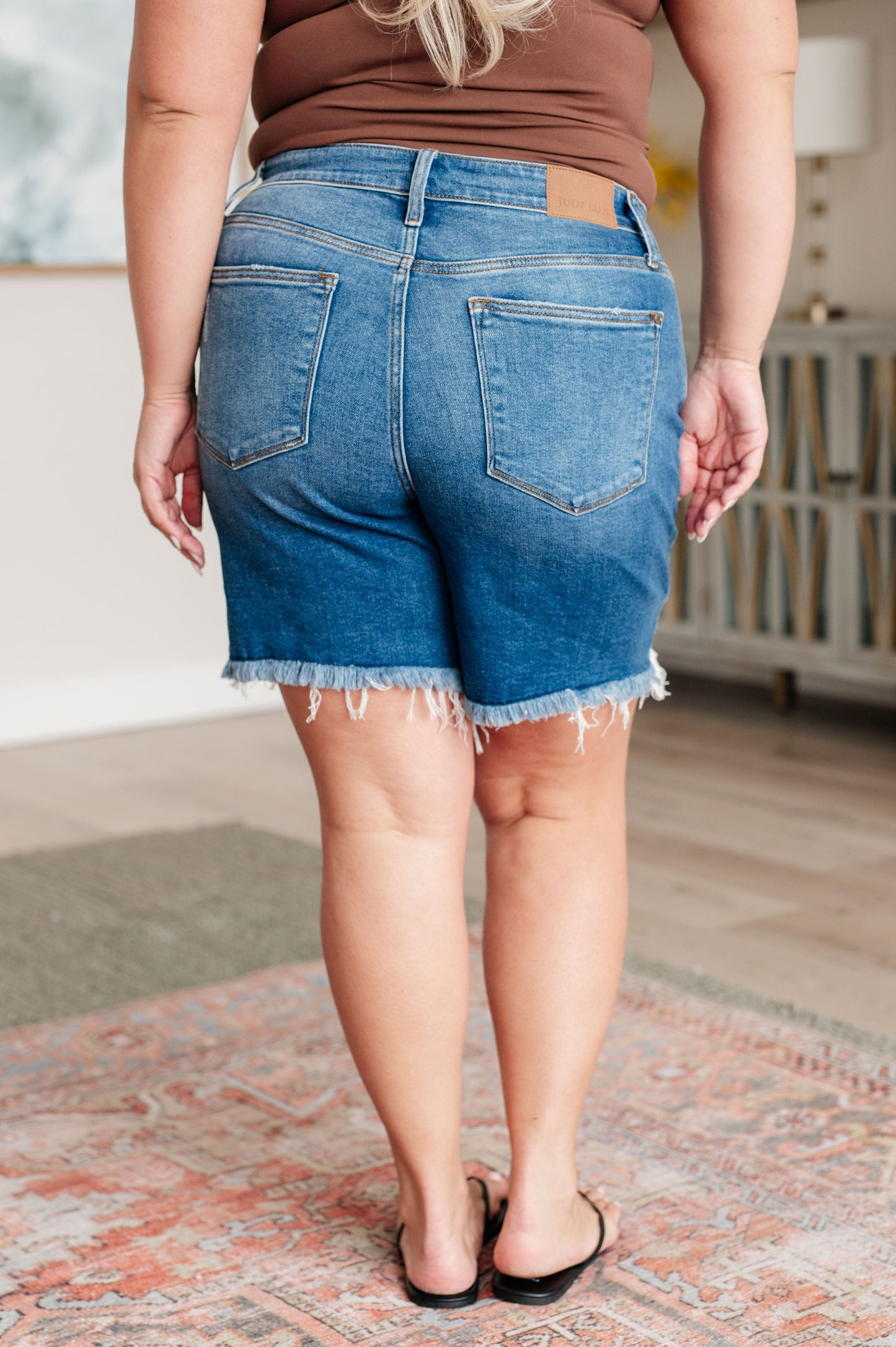 Plus size back view of Kelsa Mid Rise Cutoff Shorts highlighting pocket placement and raw hemline.