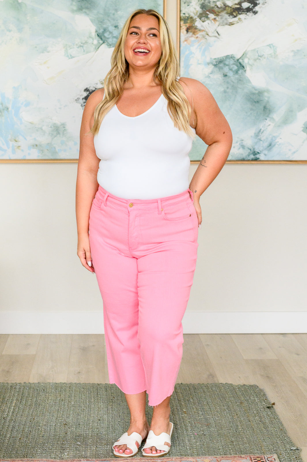 Plus size model in Lisa High Rise Wide Leg Crop Jeans in pink with tummy control fit and raw hem by Judy Blue.