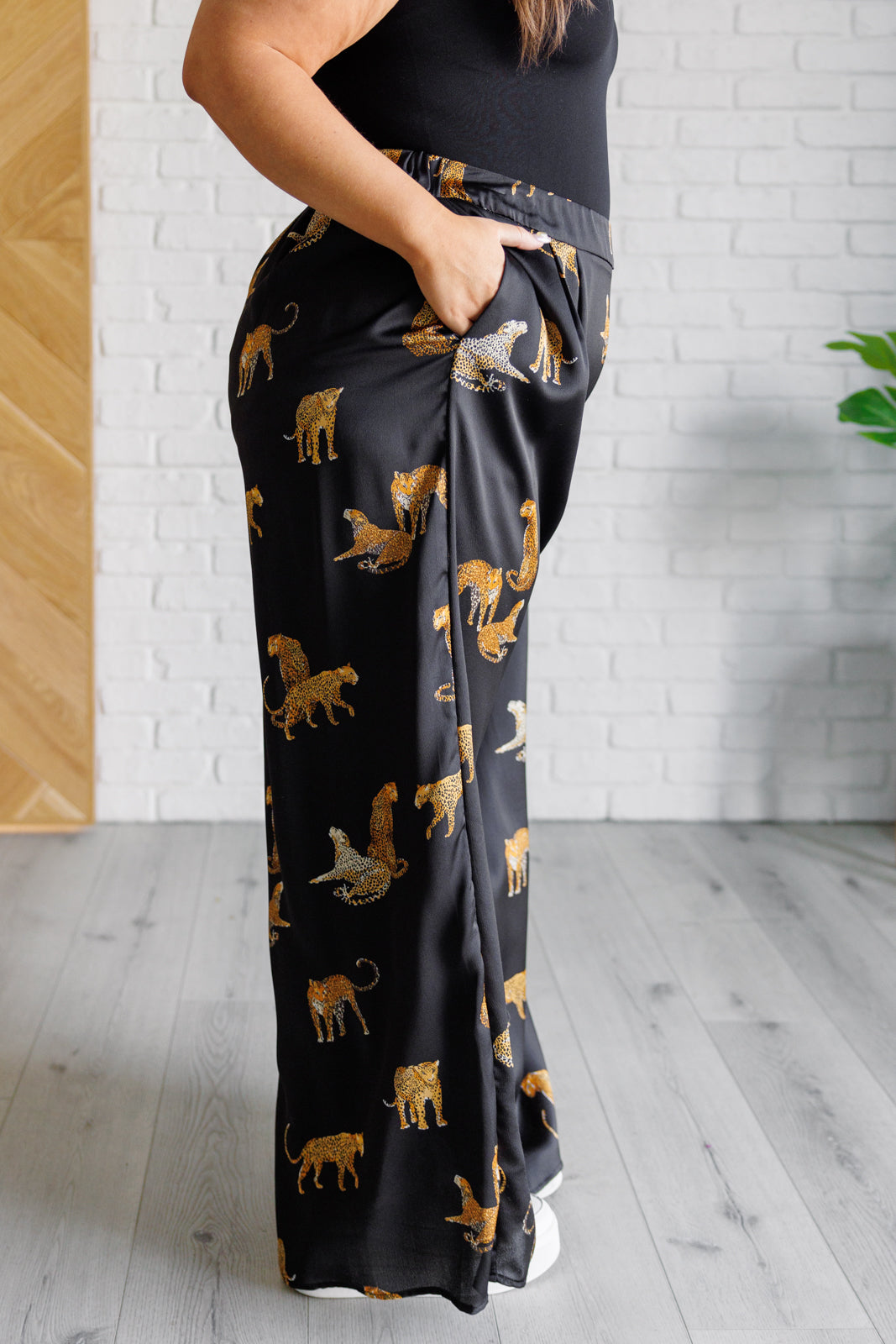 Plus size side view of Lyra Leopard Satin Wide Leg Pants showing wide-leg silhouette, shiny satin finish, and leopard imagery.