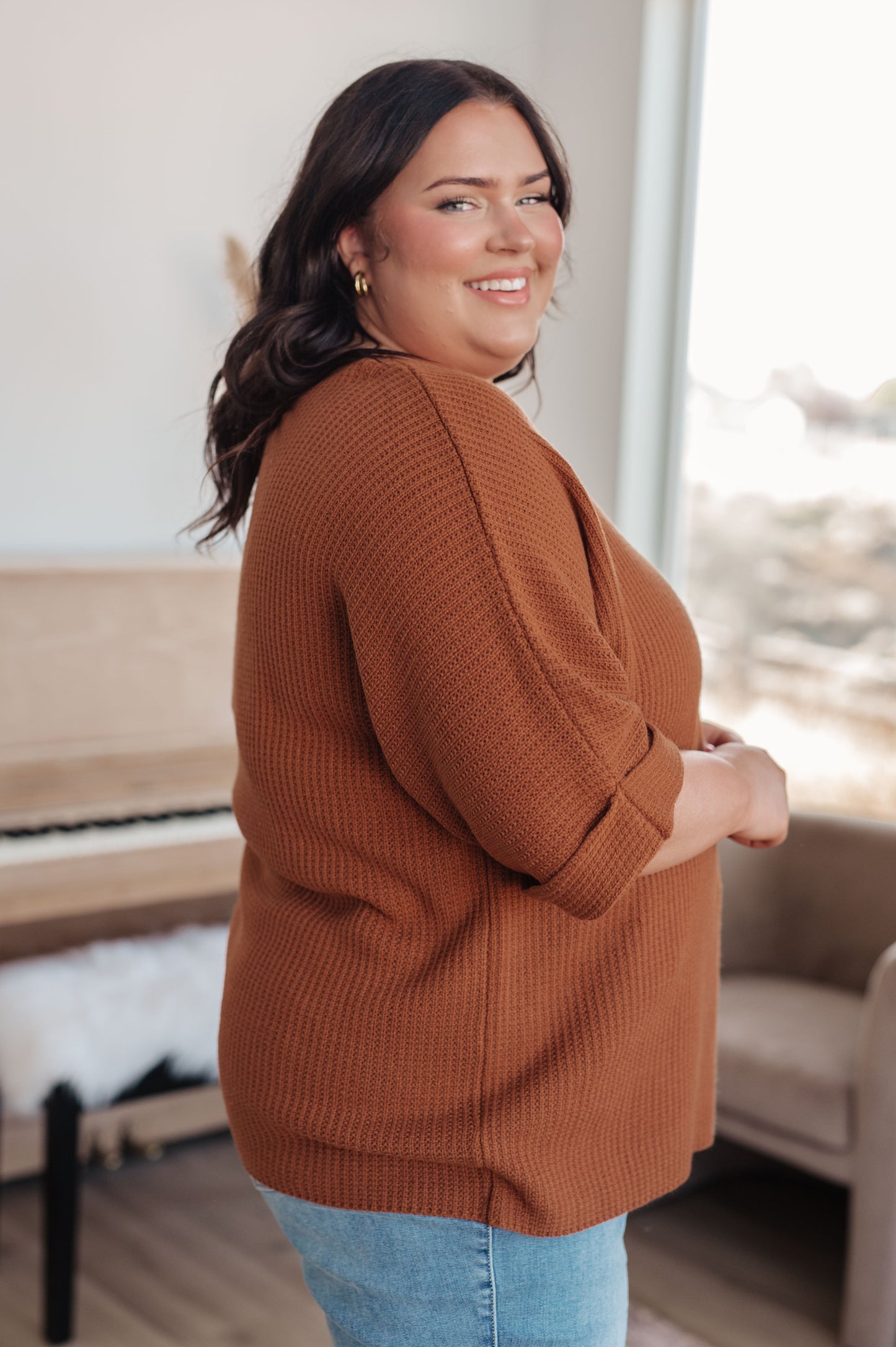 Side profile of plus size model in Zizi Rust Sweater Top, boat neckline and dolman sleeve detail