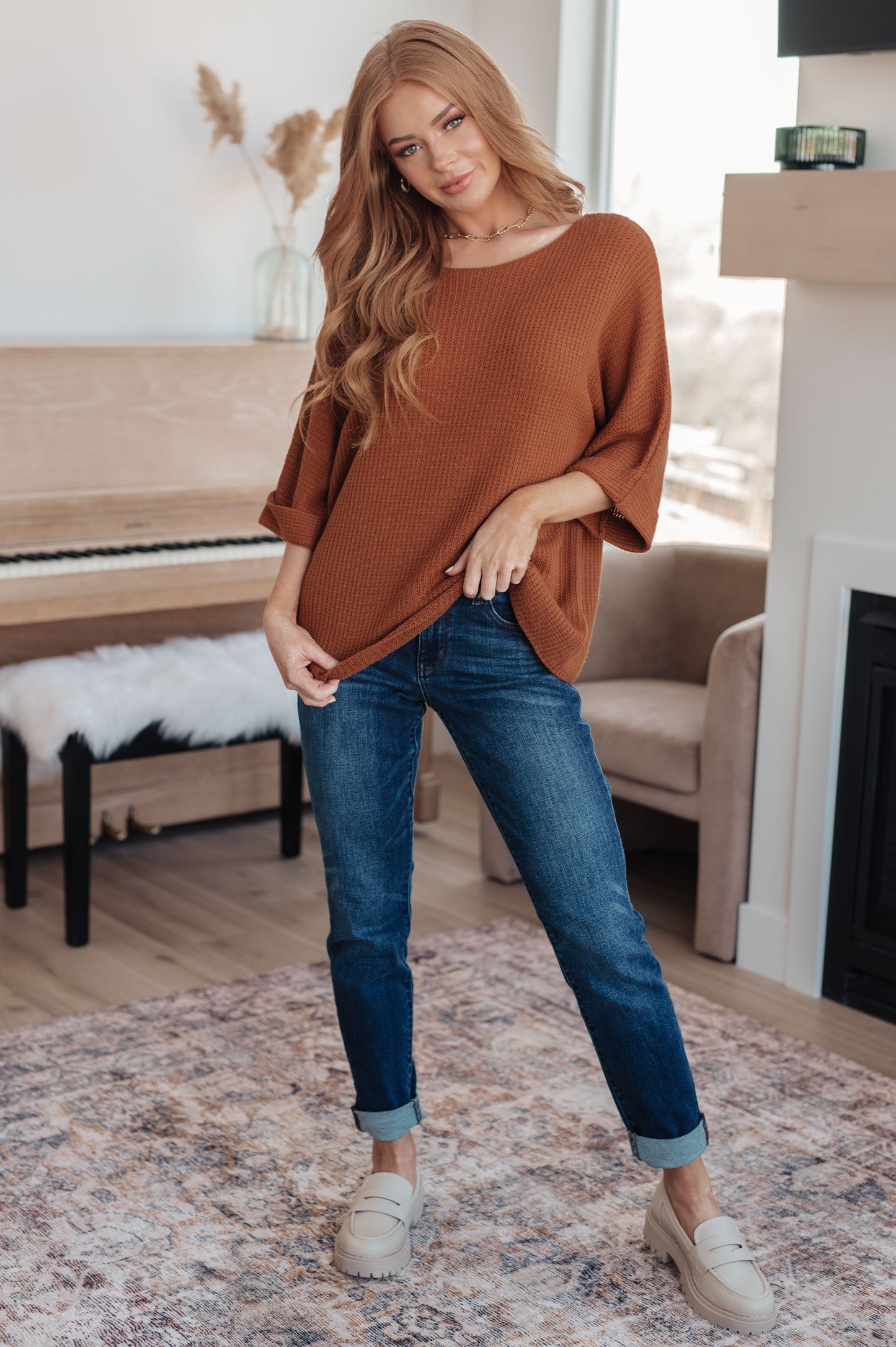 Model in Zizi Rust Sweater Top, full body styled with jeans, showing dolman sleeves and tacked cuffs