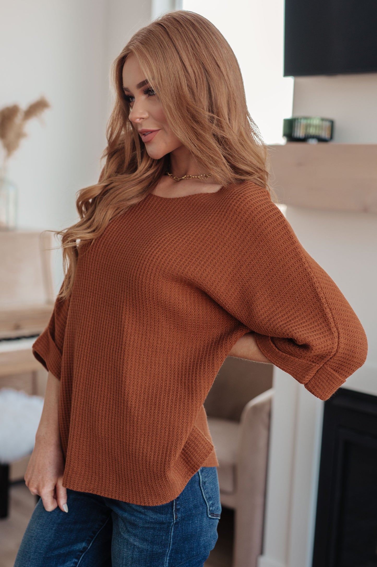 Side profile of Zizi Rust Sweater Top, relaxed fit with tacked sleeve cuffs