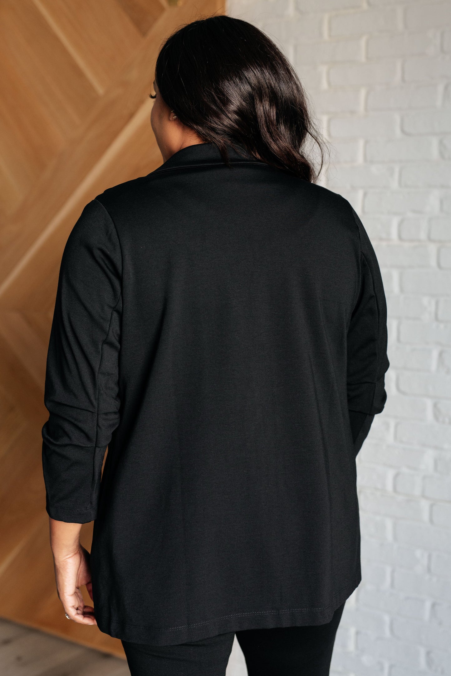 Back view of black Devi Magic Blazer, slim fit ponte knit with stylish ruched sleeves and sleek silhouette.