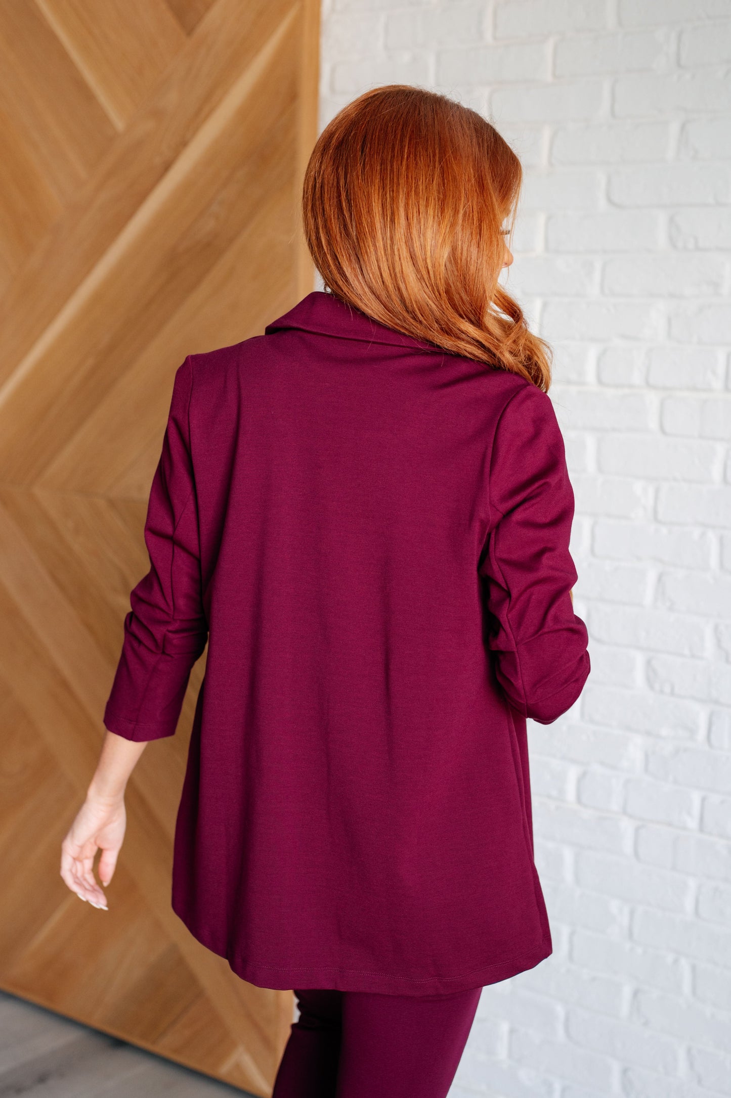Back view of women’s wine blazer with ruched 3/4 sleeves and modern chic look.