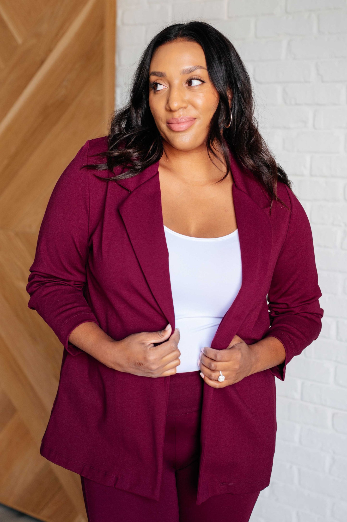 Plus size model in wine blazer with ruched sleeves and ponte knit fabric comfort.