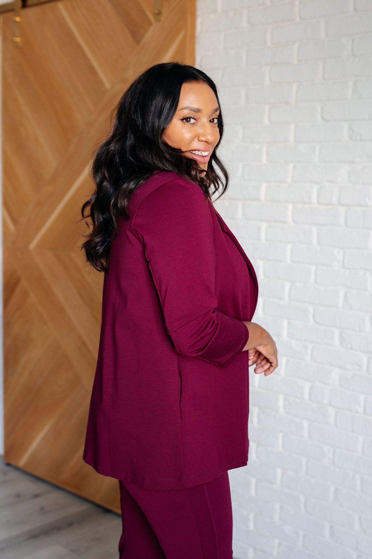 Side view of plus size wine blazer with notched lapel and open front silhouette.
