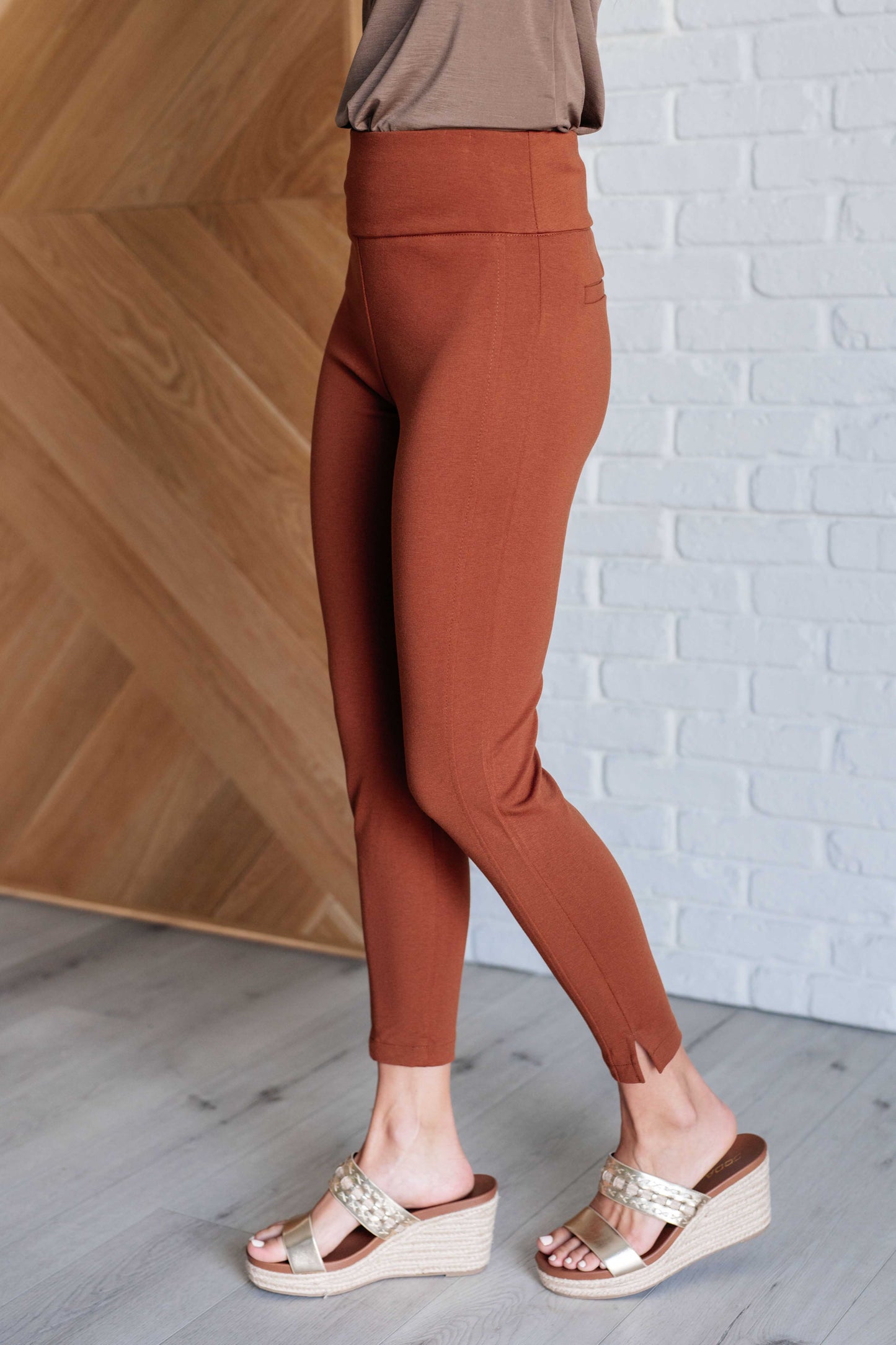 Side view of Rust Midge Magic Skinny Pants showing slim fit, tuxedo stripe detail, and flattering high-rise waist.